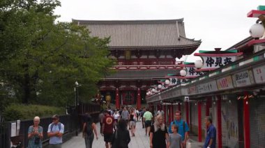 Asakusa, Tokyo 'daki Senso ji kırmızı kapısı ve fenerinin gündüz görüş açısı geniş. Kalabalık yürür ve Nakamise dori boyunca yürür dükkanlar ve fenerler ile kapalı ışık altında.