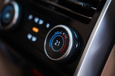 21C 'ye ayarlanmış bir iklim kontrol kadranına odaklanır, maviden kırmızıya halka, yumuşak dokunmatik siyah süs, metalik bezel ve simgeler, yüzeysel alan derinliği, parlak yansımalar.