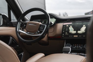Range Rover kokpitine yakın bir yerde deri süsleme, dijital küme ve geniş dokunmatik ekran var. Koltuk masajı ve kapalı servis bölümünde iklim kontrolleri, hafif ışıklandırma..