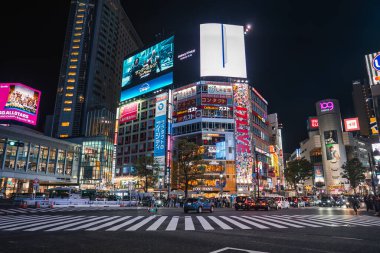 QFRONT ve Scramble Square cepheleriyle Tokyo 'da Shibuya Geçidi' nin gece görüşü yaya geçidinde kalabalıklar ve taksiler, dükkanların üzerinde parlak Japon reklamları, elektrik şehir enerjisi