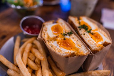 Tokyo 'da reçelli yumurta sarısı, ot, patates kızartması ve ketçap içeren Japon yumurtalı sandviçin yakın görüntüsü, sıcak tonlar ve sığ alan dokusunun derinliği.