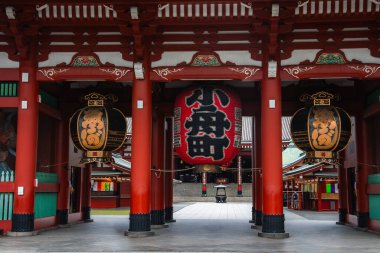 Asakusa, Tokyo 'daki Senso ji' deki Kaminarimon kapısının yakın görüntüsü, siyah kanjili kırmızı fener, süslemeli yan fener, kırmızı sütunlar, sessiz bir erken an, ötesindeki sancaklar..