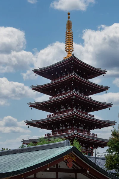 Tokyo, Asakusa 'daki Senso ji tapınağının çatıları üzerinde altın yüzgeçli koyu kırmızı pagoda. Kabarık bulutlar ve mavi gökyüzü, gezintiye uygun gündüz manzarası..