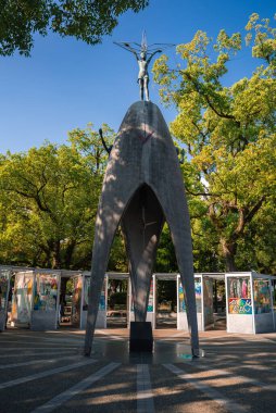 Hiroşima Barış Anıt Parkı 'ndaki anıt, elinde vinç, beton kemerli vinç ve yeşil ağaçların altında sergilenen origami vinç ve sanat eserlerini gösteriyor..