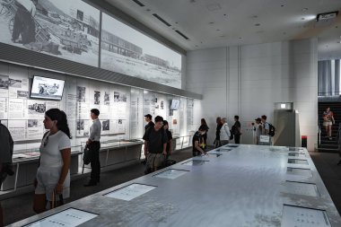 İnsanlar Hiroşima, Japonya 'da duvar panelleri, fotoğraflar, zaman çizgileri ve cam ekran tabloları üzerinde çalışıyorlar. Panoramik tarihi bir fotoğraf şeridi, düşünceli bir şekilde hareket ederlerken duvarda yükseliyor..