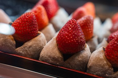 Japonya, Osaka 'da bir tepside kakao tozlu mochi ve parlak çileklerle Ichigo Daifuku' yu kapatın. Ilık ışık ve sığ derinlik vurgu dokusu ve zanaat.
