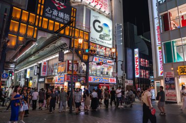 Gece Osaka Dotonbori 'de kalabalık Shinsaibashi suji tabelasının, neon panoların ve kanji mağazalarının önünde çok katlı cephelerde parlıyor..