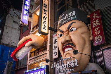 Osaka Dotonbori 'deki gece sokağı Kushikatsu Daruma cephesini gösteriyor. Kızgın şef başı, dev suşi eli ve dikey neon tabelaları, canlı renkler, keskin kontrast..