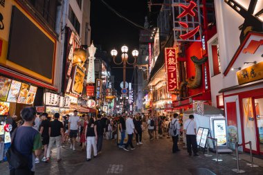Gece Osaka 'daki Dotonbori caddesi manzarası, neon tabelalar, altın ejder cephesi, büyük kırmızı ramen işareti, kalabalık kalabalık, süslü lambalar, parlak ışıklar, derin perspektif.