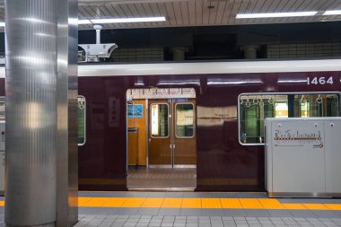 Kestane rengi tren 1464 'te bir yeraltı Osaka platformunda durur. Kapılar sarı bir iç kısma açılır. Tırabzanlar, Japonca işaretler, dokunsal kaldırımlar, tırtıklı sütunlar ve floresan lambalar..