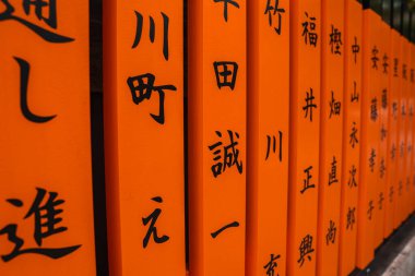 Kyoto 'daki Fushimi Inari Taisha' da siyah kanjili turuncu torii sırasını kapat. Belirsizlik açısı, sığ derinlik temel karakterleri, ritmi ve geleneği vurguluyor.