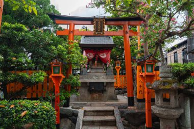 Japonya 'da Kyoto' da küçük bir tapınak yakut ve fenerlerin arasında yer alır. Bir taş sunak, kırmızı perdeli onur, tilki heykelleri, plaklar ve gün ışığında bir taş fener belirir..
