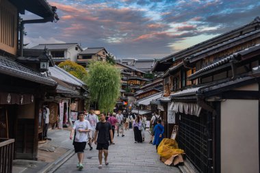 Yaya gezginleri, Ninenzaka yakınlarındaki Kyoto Higashiyama 'da taştan bir şerit boyunca yürürler, noren ve fenerlerle Machiya' yı geçerler, sarkık bir söğüt ve alacakaranlıkta sıcak dükkan ışıkları..