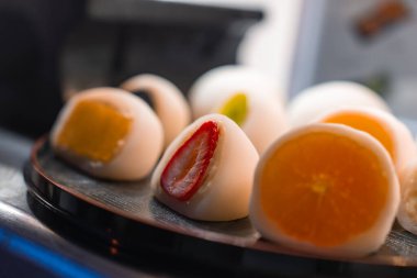 Çilekli, portakallı, mangolu ve kivili daifuku mochi Japonya 'nın Kyoto şehrinde bir tepside duruyor. Sıcak, dağınık ışık ve sığ odak. Parlak meyveler ve yumuşak kabuklar..