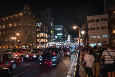 Yoğun trafik ve kalabalık Japonya 'nın merkezindeki sıcak sokak lambaları altında hareket ediyor. Taksiler ve otobüsler Shijo Kawaramachi ve Gion caddelerinin yakınındaki yoğun bir akşamda..