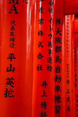 Yakından bakınca Kyoto 'daki Fushimi Inari Taisha' daki siyah kanji yazıtlarını görüyoruz. Yumuşak gün ışığı ve sığ odak, parlak ahşap ritmi ortaya çıkarıyor.