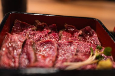 İnce mermer et dilimleri Japonya 'nın Nara kentindeki bento kutusunda duruyor. Ilık iç ışık, sığ derinlik ve kavrulmuş izler vurgu dokusu, rengi ve zanaat..