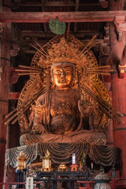 Altın yaldızlı bir Budist heykeli, Japonya 'nın Nara kentindeki geniş ahşap bir salonda, nilüfer ağacından yapılma kuleler, sunaklar ve sıcak bir ışık altında emzirilmiş sütunlarda bulunur..