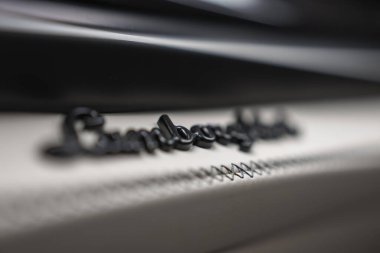 Sığ bir derinlik Lamborghini betik rozetini gösterir açık deri üzerine zigzag kontrastlı dikişler, sıkı odak ve yumuşak dağınık ışıklandırmalı kremalı bokeh.