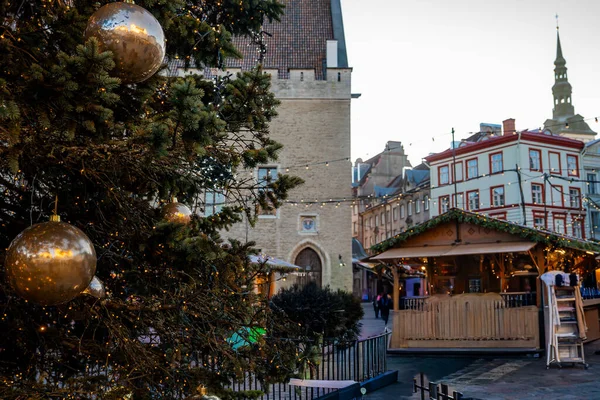 Büyük bir Noel ağacı kaldırımların ve Tallinn Belediye Binası 'nın yanında parıldıyor. Pazar yerleri alacakaranlıkta parıldıyor. St. Nicholas Kilisesi kışın Eski Kent' in üzerinde yükseliyor..