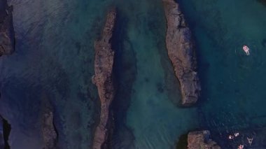 Yukarıdan bakıldığında Madeira, Portekiz 'de bazalt çıkıntıları ve turkuaz havuzlar görülüyor. Yüzücüler sıcak akşam ışığında yüksek kontrastlı su tonlarıyla hafif dalgalanmalar yaratırlar..