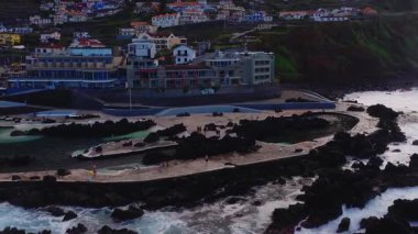 Öğleden sonra hava gösterileri, turistlerin turkuaz havzalarda yürüyüp yüzdüğü Porto Moniz lav havuzları, Atlantik dalgaları, gezinti alanları ve Madeira 'nın yamaç köyü..