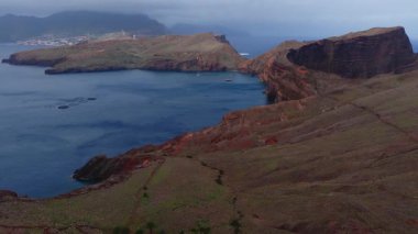 Havadan çekilen görüntülerde pas kırmızısı uçurumlar, dar burunlar, Atlantik körfezi, su kalemi, yürüyüş yolları, uzak yerleşim yerleri ve hafif bulutlu rüzgar türbinleri görülüyor..