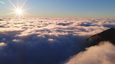 Hava manzarası Pico do Arieiro 'nun engebeli tepelerini ve Madeira' daki orman yamaçlarını gösteriyor. Bulutlar, düşük güneş patlaması, ılık pembeler ve serin maviler ve pürüzsüz bir hareketle tersine dönüşüyor..