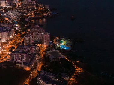 Funchal, Madeira, Portekiz 'deki hava sahnesi otel kulelerini, turuncu caddeleri ve Atlantik kıyısında yansıyan turkuaz dairesel havuzu gösteriyor..