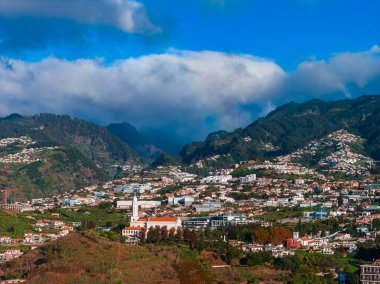 Madeira Adası 'ndaki funchal, yamaçlarda, terracotta çatılarında beyaz binalar, yüksek bir kilise kulesi, yeşil teraslar ve gevrek bulut bulutu altında kıvrımlı yollar gösteriyor..