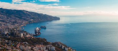 Funchal, Madeira, Portekiz 'in hava manzarasında teraslı tepeler, liman ve seyir terminali kıvrımlı dalgakıran tarafında bir yolcu gemisi ve gün ışığında Cabo Girao görülüyor..