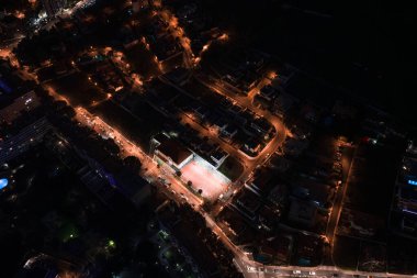 Hava gece görüşüne göre Funchal, Madeira, Portekiz 'deki parlak bir plazanın etrafında sıcak kehribar sokaklar var. Bir çan kulesi kıvrımlı yolların, karanlık blokların, yüksek kontrastlı ışıkların yanında durur..