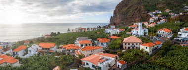 Turuncu çatılı, bembeyaz evler yeşil terasların ve Atlantik kıyısında engebeli bir uçurumun kenarında otururlar. Çan kulesi olan küçük bir kilise, palmiye çizgili bir güvertenin yanında duruyor..