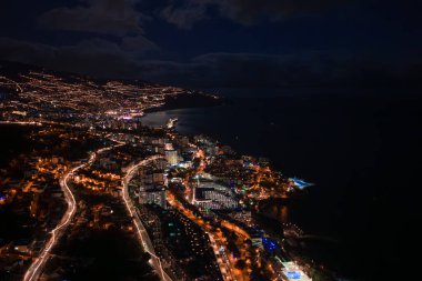 Portekiz, Madeira 'daki Funchal' ın gece görüşü teraslı tepeler, kıvrımlı kıyı şeritleri, Lido Güvertesi yakınlarındaki marina ışıkları, uzun süreli ışıltı ve karanlık Atlantik 'i gösteriyor..