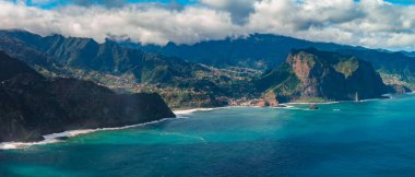 Madeira 'nın kuzey kıyısındaki hava sahili dik yeşil dağlar, volkanik burunlar, dik kayalıklar Sao Vicente ve Ponta Delgada yakınlarındaki koylarda güpegündüz sörf gösteriyor..