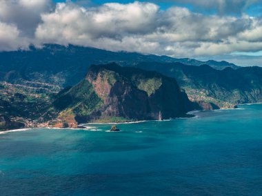 Geniş görüş açısı, Portekiz 'in Madeira Adası' ndaki bazı kayalıkları, beyaz kum koylarını ve köyleri gösteriyor. Hareket eden bulut gölgeleri, turkuaz su ve açık deniz kayaları..