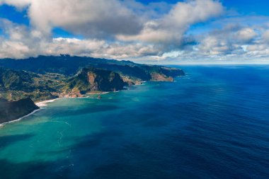 Hava görüntüsü Madeira 'nın kuzey kıyısı kayalıklarını, teraslı köyleri ve Ponta de Sao Lourenco ve Porto Moniz yakınlarında bulutlu gölgelerle öğleden sonra güneşini gösteriyor..