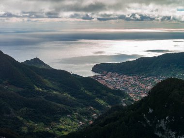 Madeira 'nın Madeira' nın kuzey kıyısı Machico ya da Santana yakınlarında, dik orman dağları hilal körfezi ile buluşur, deniz kıyısında küçük bir kasaba, yumuşak öğleden sonra ışığı.