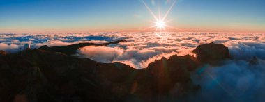 Sabahın erken saatlerinde Portekiz 'in Madeira Adası Pico do Arieiro şehrinde güneş bulutları delip geçerken bir yıldız patlaması meydana getirir..