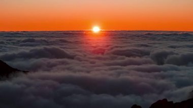 Hava gündoğumu Pico do Arieiro, Madeira 'da bulutların yükseldiğini gösteriyor. Sivri tepeler çerçeve köşeleri, ılık kehribar gradyanı katmanlar kaydıkça serin sis kontrastı.