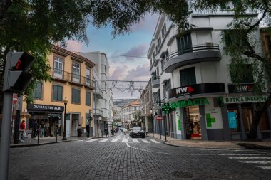 Funchal, Madeira 'daki Cobblestoned caddesi pastel cephelerden ve Art Deco balkonlarından geçiyor. Neon yeşil Farmacia Botica Inglesa tabelası ve Quiksilver marka köşeler arabalar yokuş aşağı giderken.