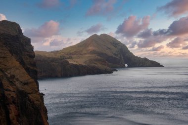 Portekiz, Madeira 'daki Ponta de Sao Lourenco' da kayalık bir burnu katmanlı kayalıklar ve bir kemer delip geçer. Sıcak ışık kurak, çizgili yamaçlara dokunur pembe bulutlar sürüklenirken.
