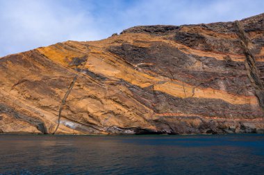 Sao Lourenco Ponta de Sao Lourenco, Madeira, Portekiz 'de donuk su, pas ve kömür şeritli dramatik sahil uçurumları yükseliyor. İnce bulutların altında gün ışığı, görülebilir deniz mağarası..