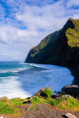 Madeira engebeli deniz kayalıkları Ponta de Sao Lourenco yakınlarındaki Atlantik 'e dökülüyor. Volkanik kaya yüzeyleri, doymuş gün ışığı, köpüklü turkuaz dalgalar ve yeni yağan yağmurlar.