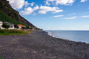 Çamurlu kıyı şeritleri Portekiz 'in engebeli Madeira kıyı şeridi, beyazlatılmış evler ve sarp bir volkanik uçurum üzerinde muz terasları, sakin Atlantik suları ve yumuşak öğleden sonra ışığı.
