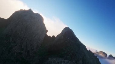 Portekiz 'in Madeira adasında gün batımında Pico do Arieiro' da bulutların üzerinde uçmak. Bulutların üstünde sihirli günbatımı manzarası dağ sıraları ve yürüyüşçülerin yanında uçuyor..
