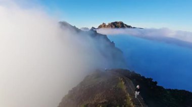 Portekiz 'in Madeira adasında gün batımında Pico do Arieiro' da bulutların üzerinde uçmak. Bulutların üstünde sihirli günbatımı manzarası dağ sıraları ve yürüyüşçülerin yanında uçuyor..