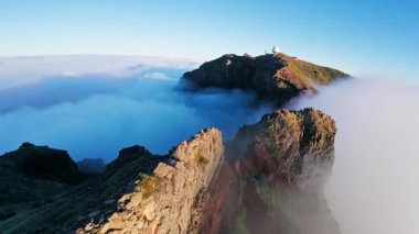 Portekiz 'in Madeira adasında gün batımında Pico do Arieiro' da bulutların üzerinde uçmak. Bulutların üstünde sihirli günbatımı manzarası dağ sıraları ve yürüyüşçülerin yanında uçuyor..