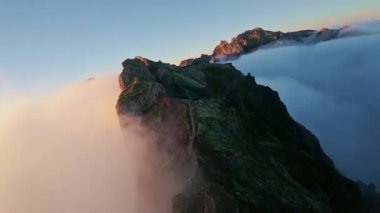 Portekiz 'in Madeira adasında gün batımında Pico do Arieiro' da bulutların üzerinde uçmak. Bulutların üstünde sihirli günbatımı manzarası dağ sıraları ve yürüyüşçülerin yanında uçuyor..
