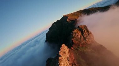 Portekiz 'in Madeira adasında gün batımında Pico do Arieiro' da bulutların üzerinde uçmak. Bulutların üstünde sihirli günbatımı manzarası dağ sıraları ve yürüyüşçülerin yanında uçuyor..